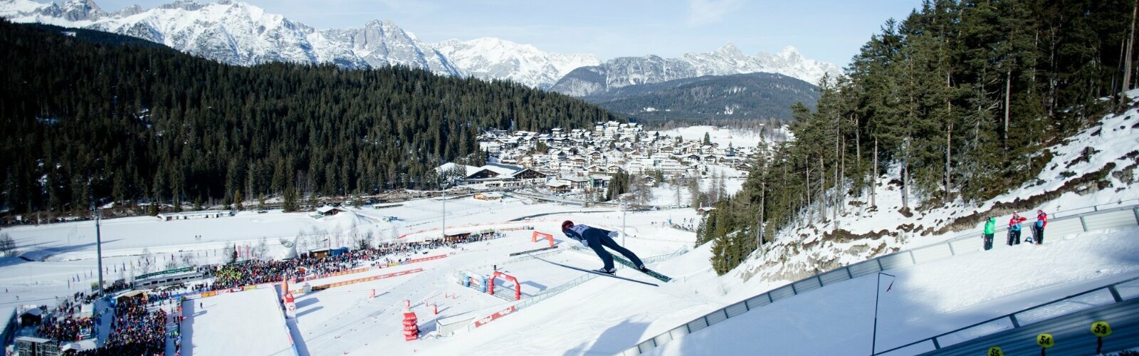 Skispringer in der Luft, Viele Zuschauer, Blauer Himmel